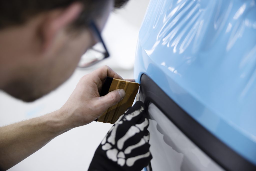 close up man wrapping car with blue cover